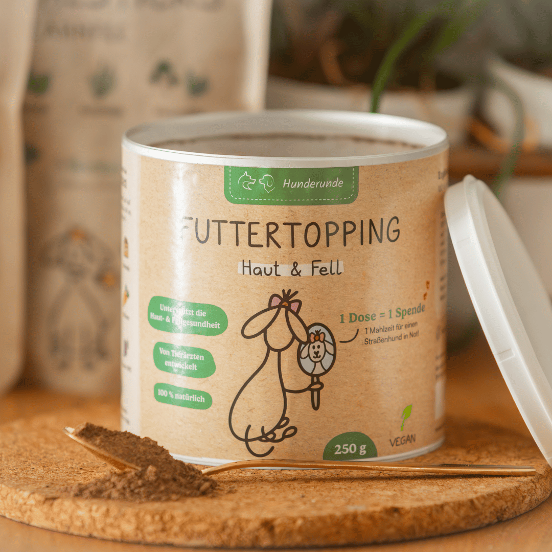 A can of Topping Vorteilspaket pet food supplement sits on a cork mat with a spoonful of powder.