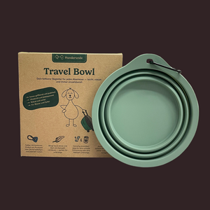 Ein grüner Hunderunde Travel Bowl kostenlos wird neben seiner braunen Verpackung gezeigt, auf der ein Cartoon-Hund abgebildet ist.